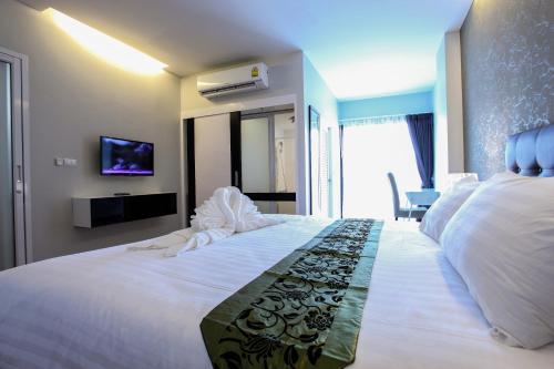 a bedroom with a large white bed and a tv at Romyen Garden Place in Nakhon Ratchasima