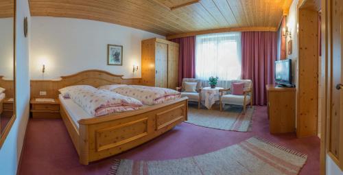 a bedroom with a bed and a table and a television at Landhaus Doris in Leutasch