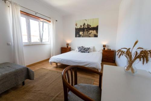 a bedroom with a bed and a table with a chair at Alaia SurfLodge in Ericeira