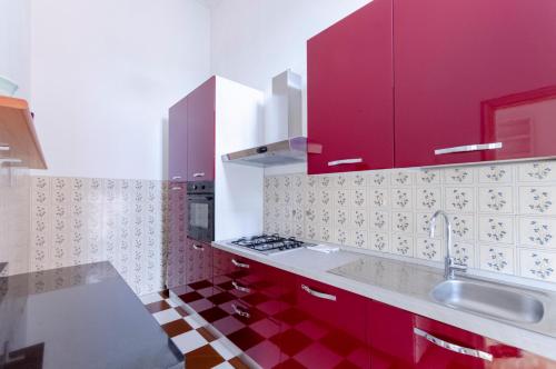 una cucina con armadi rossi e lavandino di ALTIDO Kiosk Opera House a Rapallo