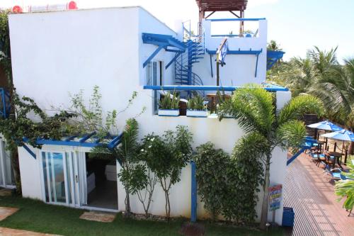 a white building with blue balconies and trees at Sollaris Ecopousada in Japaratinga