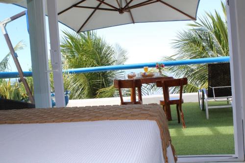 a balcony with a table and an umbrella at Sollaris Ecopousada in Japaratinga