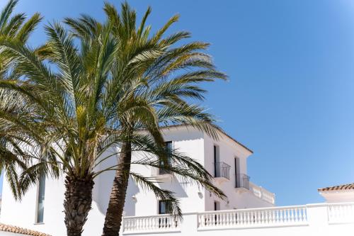 a white building with palm trees in front of it at Sighientu Resort in Capitana