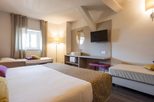 um quarto de hotel com duas camas e uma televisão em Hotel Alexandra em Locarno