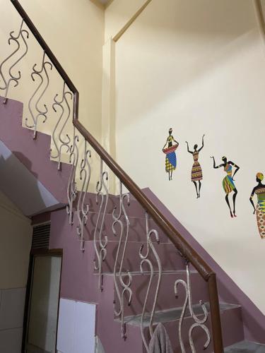 a staircase with a mural of women on the wall at Indra Paying Guest House in Varanasi