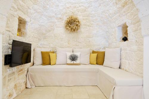 a white couch in a room with a stone wall at Trullo Natù in Alberobello