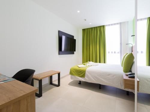 a hotel room with a bed and a desk and a television at Hotel MG Poniente in Las Palmas de Gran Canaria
