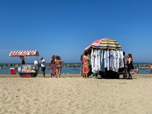 a group of people standing on a beach with an umbrella at Le Ortensie in centro e vicino al mare in Pescara