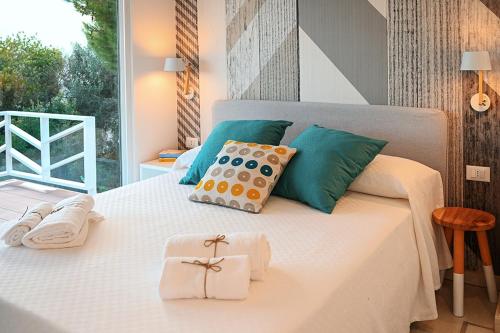 a bedroom with a white bed with green and blue pillows at Macchia Piccinna in Maruggio