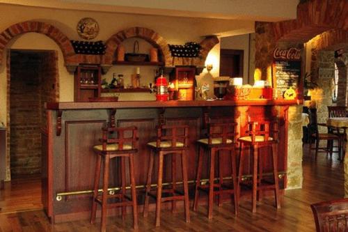 a bar with wooden stools in a room at Il Gallo Nero - Fekete Kakas Étterem és Panzió in Szombathely