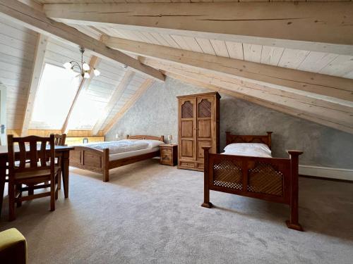a attic room with two beds and a table and chairs at Vila Liberta in Poprad