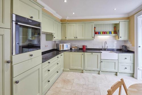 una cocina con armarios verdes y electrodomésticos blancos en Host & Stay - Muggles Mews, en Alnwick
