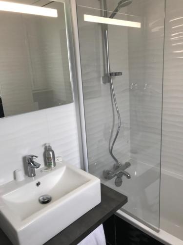 biała łazienka z umywalką i prysznicem w obiekcie Les Pastels w mieście La Roche-sur-Yon