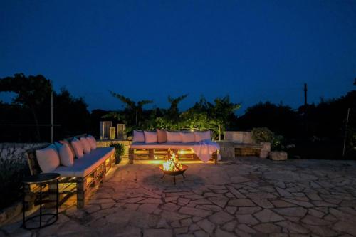 a patio with couches and a fire pit at night at Trullo Natù - private villa in Alberobello