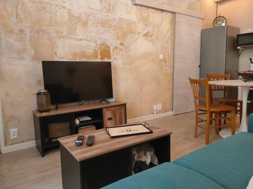 a living room with a tv and a table at La petite Arlésienne - Charmante maison de ville in Arles