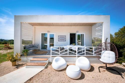 a house with white furniture on a deck at Macchia Piccinna in Maruggio
