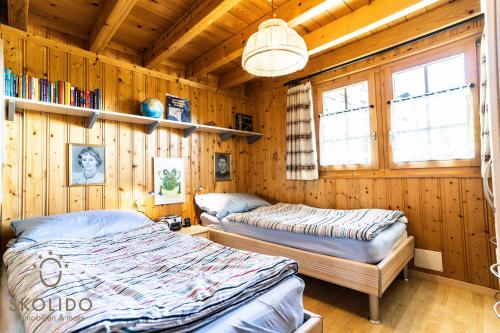 two beds in a room with wooden walls at Chalet Aletschji, 3987 Riederalp, 2. Stock in Riederalp