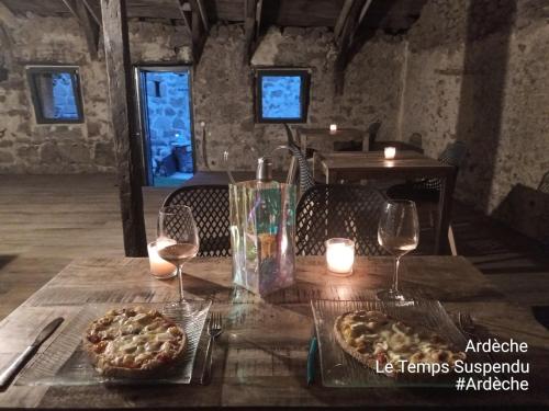 a table with two pizzas and two glasses of wine at Le Temps Suspendu in Saint-Pierreville