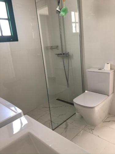 a white bathroom with a shower and a toilet at Casita Vito Fuerteventura in Costa Calma