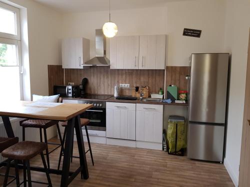 a kitchen with a stainless steel refrigerator and a table at Sommerhaus (am Landhaus von Felde) in Esens