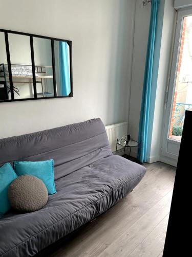 - un canapé gris dans le salon avec un miroir dans l'établissement Appartement Rue de la gare centre ville, à Quiberon