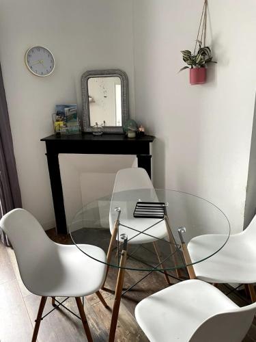 une table en verre avec trois chaises blanches et un miroir dans l'établissement Appartement Rue de la gare centre ville, à Quiberon