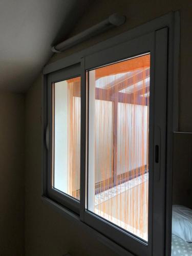 - une fenêtre en verre dans une chambre avec un lit dans l'établissement Maison Place manemeur, à Quiberon