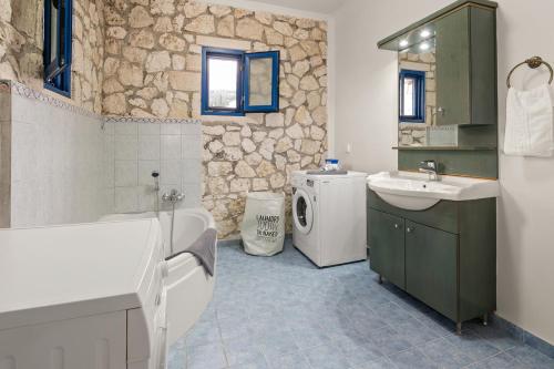 a bathroom with a tub and a sink and a washing machine at Stone House in olive Grove - former Denis Stone Villa in Trapezaki