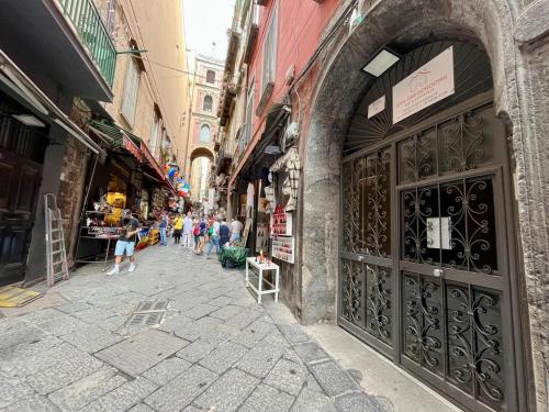 un vicolo con una grande porta e gente che cammina per strada di SanGregoRooms a Napoli