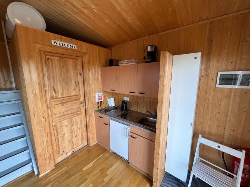 a kitchen with a white refrigerator and a wooden wall at Gotta Cottages in Selfoss