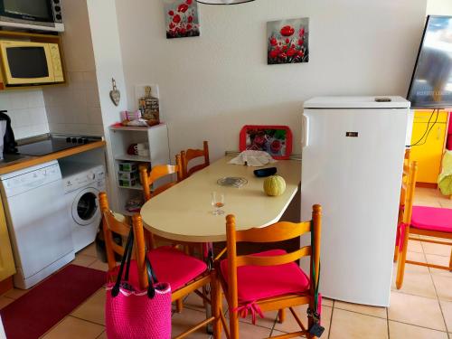 une cuisine avec une table, des chaises et un réfrigérateur dans l'établissement Appartement mer, à Plage dʼArgelès
