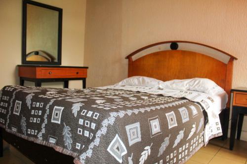 a bed with a black and white blanket and a mirror at Hotel Regis in Monterrey