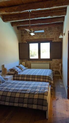 a bedroom with two beds and a stone wall at Lo Indiano, casa de turisme rural in Prat de Compte