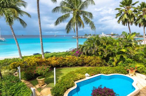 einen Pool mit Palmen und dem Meer im Hintergrund in der Unterkunft Port St. Charles in Saint Peter