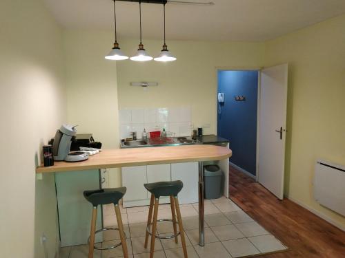 a kitchen with a counter with stools and a blue door at Bonvallet - Studio paisible et chaleureux avec balcon in Amiens