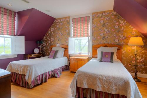 two beds in a room with purple walls and windows at Nesselrod on the New in Fairlawn
