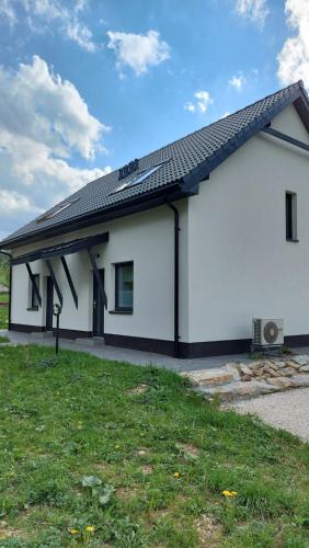 a white house with a black roof at Domek nad potokiem in Stronie Śląskie