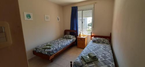 2 camas en una habitación pequeña con ventana en Departamentos Saavedra dto A y B en Viedma