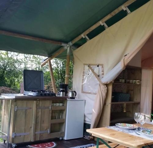 a tent with a table and a tv on it at La lodge du Refuge in Valigny