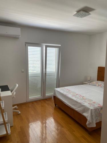 a bedroom with a bed and two sliding glass doors at Apartmani Mia in Kali