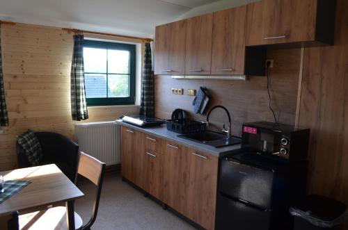 a kitchen with wooden cabinets and a sink and a table at ŠUMAVSKÉ zaSTAVENÍ in Stachy