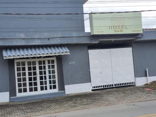 a building with two white doors and a sign on it at Hotel Beira Rio Guararema in Guararema