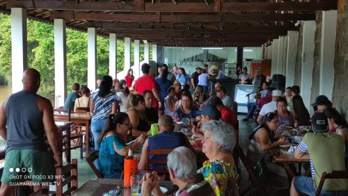 a crowd of people sitting at tables in a restaurant at Hotel Beira Rio Guararema in Guararema