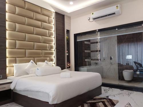 a bedroom with a large white bed and a bathroom at Grand Beach Resort in Mandarmoni