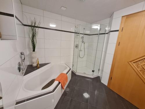een witte badkamer met een douche en een bad bij Appartement Gsaller in Hopfgarten in Defereggen