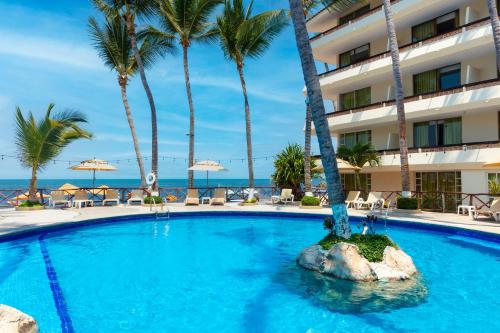 a swimming pool in front of a hotel with palm trees at Las Palmas by the Sea All Inclusive in Puerto Vallarta