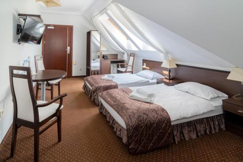 ein Hotelzimmer mit 2 Betten und einem Tisch in der Unterkunft Hotel Pod Filarami in Czeladź