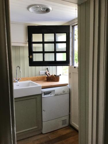 una pequeña cocina con fregadero y lavavajillas en The Blue Cottage, en Antrim