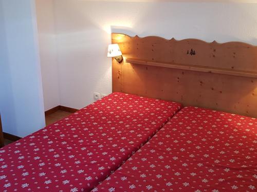uma cama vermelha com um edredão vermelho em Chalet La Joue du Loup, 3 pièces, 8 personnes - FR-1-504-5 em Le Dévoluy