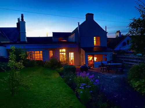 una casa con las luces encendidas en el patio en Cosy country cottage in Central Scotland en Buchlyvie